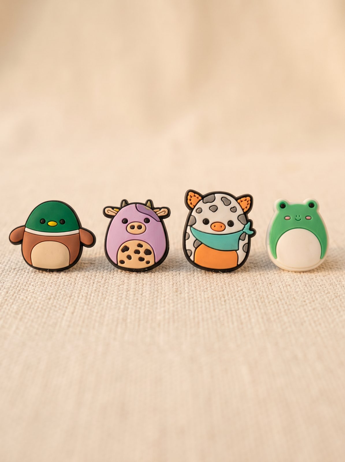 Squishy rubber animal charms — a duck, a cow and frogs